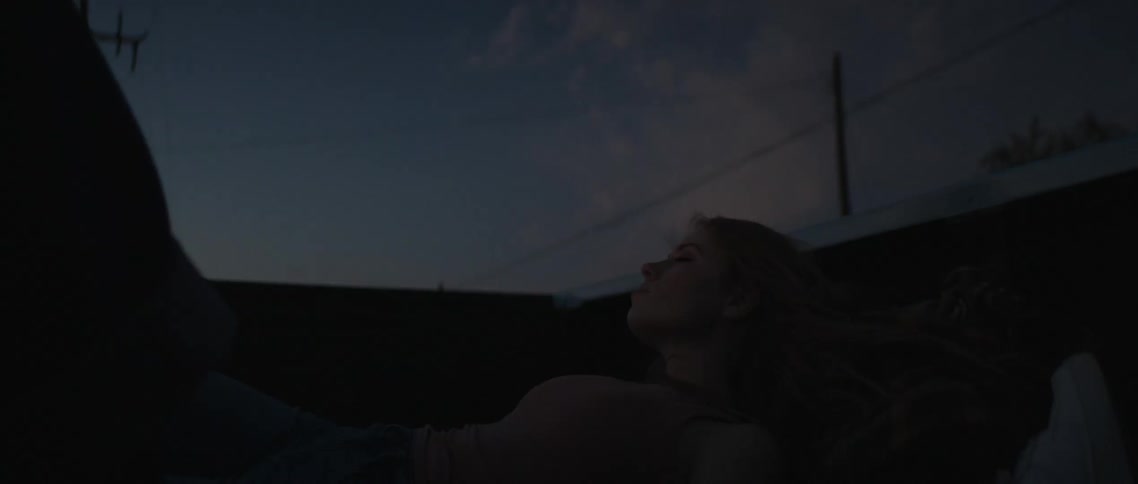 Young woman laying on the back of a moving truck at night