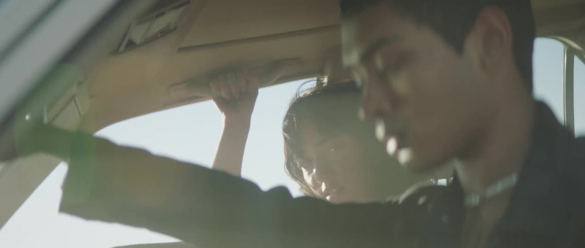 A man and a woman in a vehicle with smoke with the sky and clouds in the background