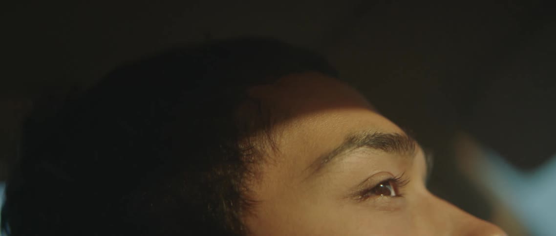Sunlight reflecting on a young man face sitting on a car parked outdoors