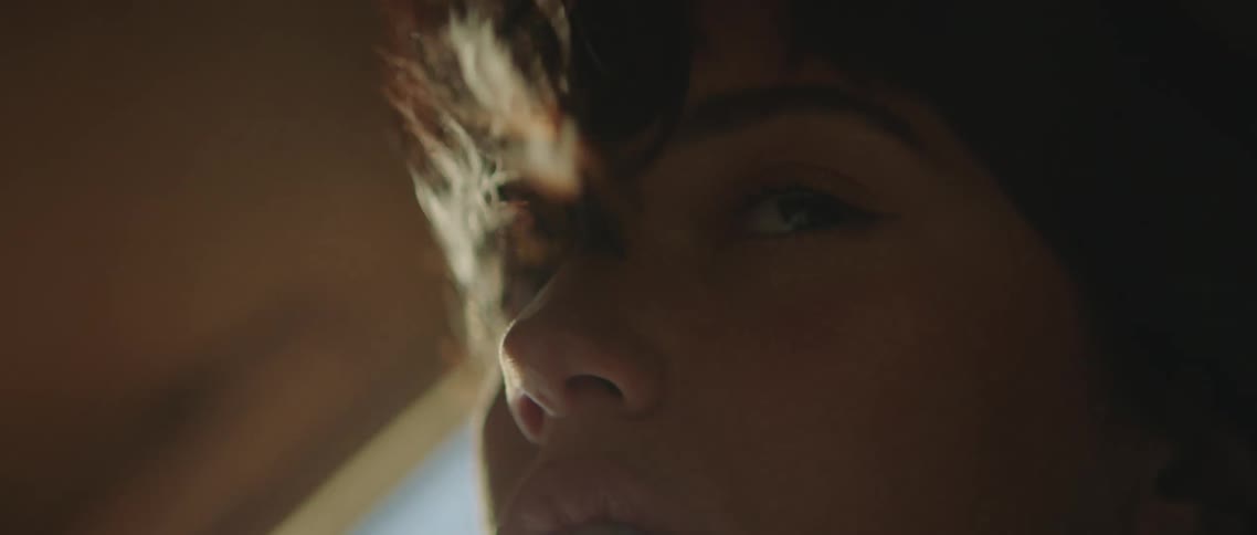 Close up of a young woman sitting on the passenger seat of a car surrounded by wind and smoke in the sunset