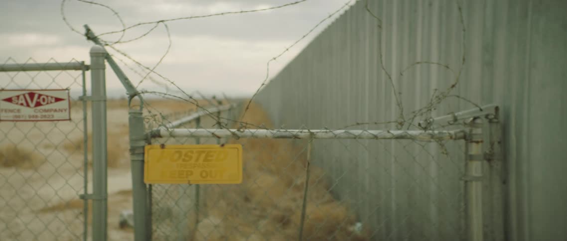 A chain link fence protects a large isolated building
