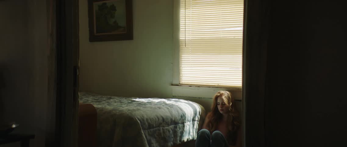 A woman sitting on the floor of a room looking sad