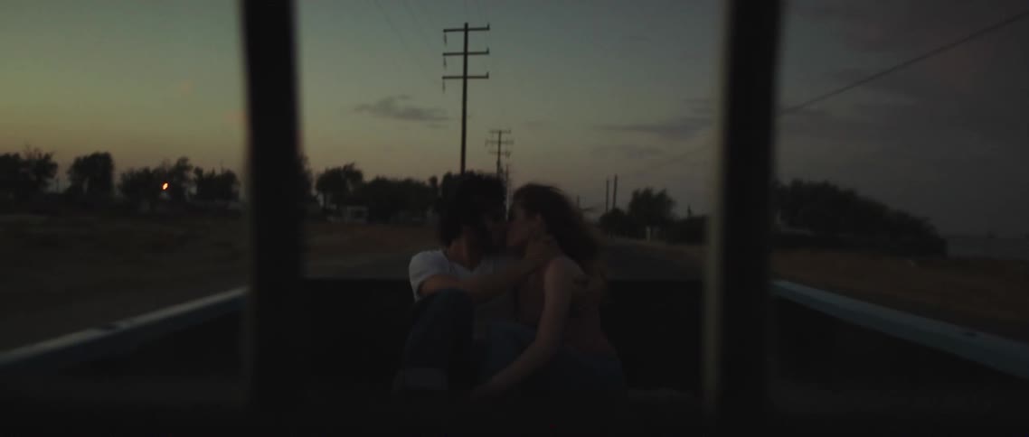 A boyfriend and girlfriend kissing in the back of a truck