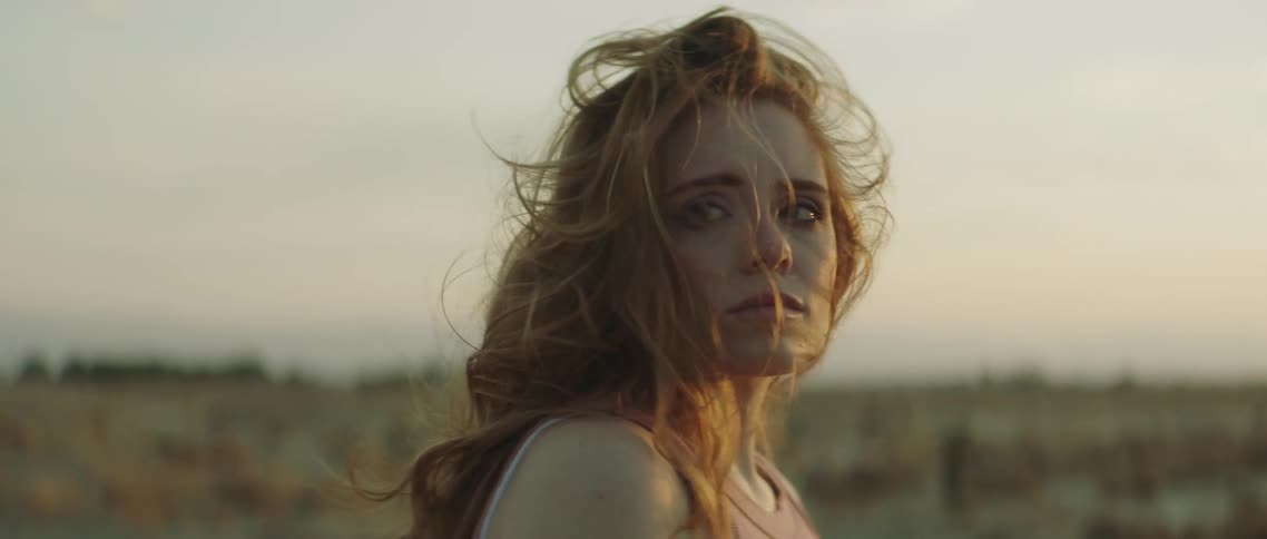 A woman looks over at a man in the desert