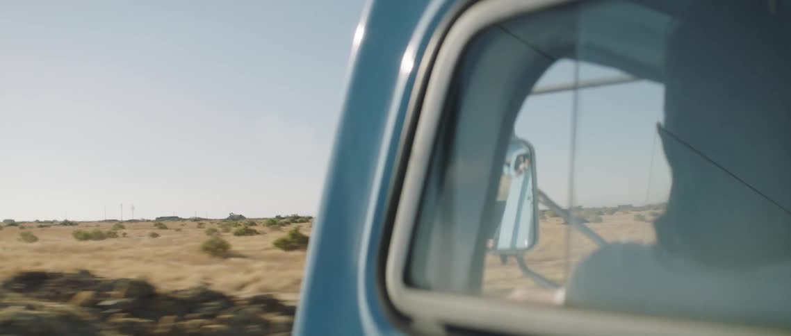 A person sitting in the vehicle with a landscape sky and clouds in the background