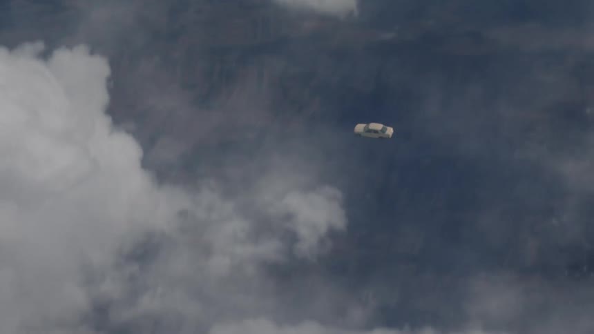 Cloudy sky and a car is falling and tumbling to the ground below