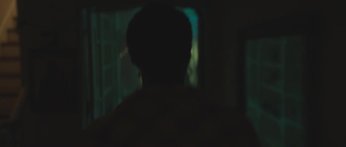 A man walking through a house with a party with people with walls and doors in the background