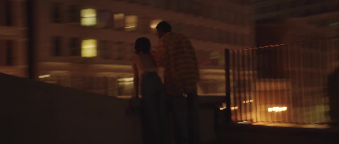 Young couple standing on the roof of a building at night