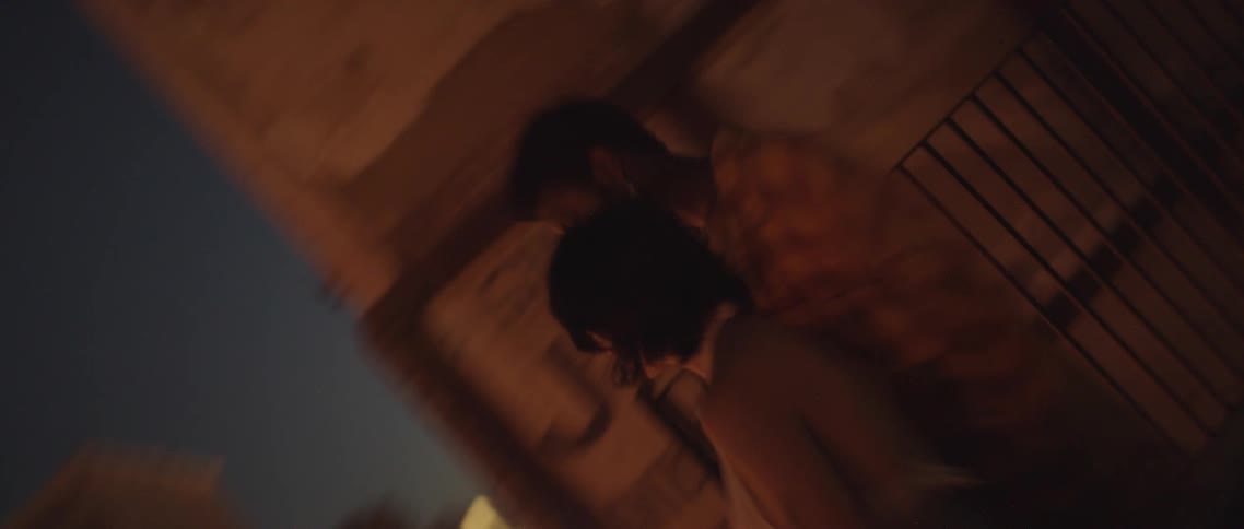 Young couple standing on the roof top of a building in the city at night