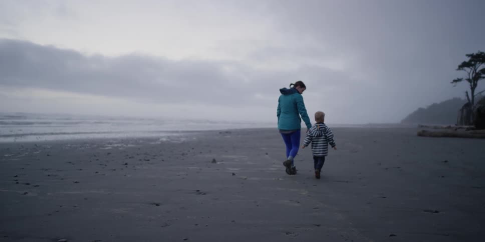 A woman and her son walk along the beach