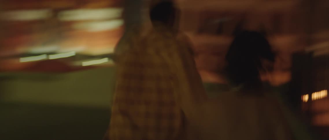 A man and woman are holding hands as they walk then look down