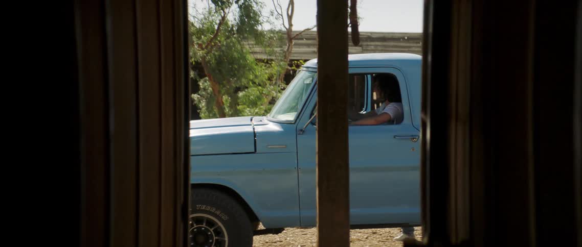A woman hurriedly runs out of her house and jumps into a waiting blue pickup truck
