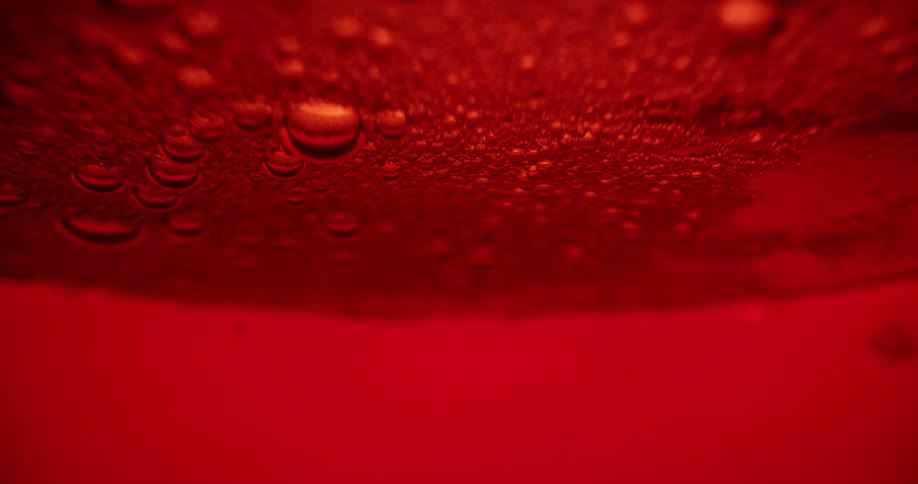 Bubbles floating to the surface of a red liquid