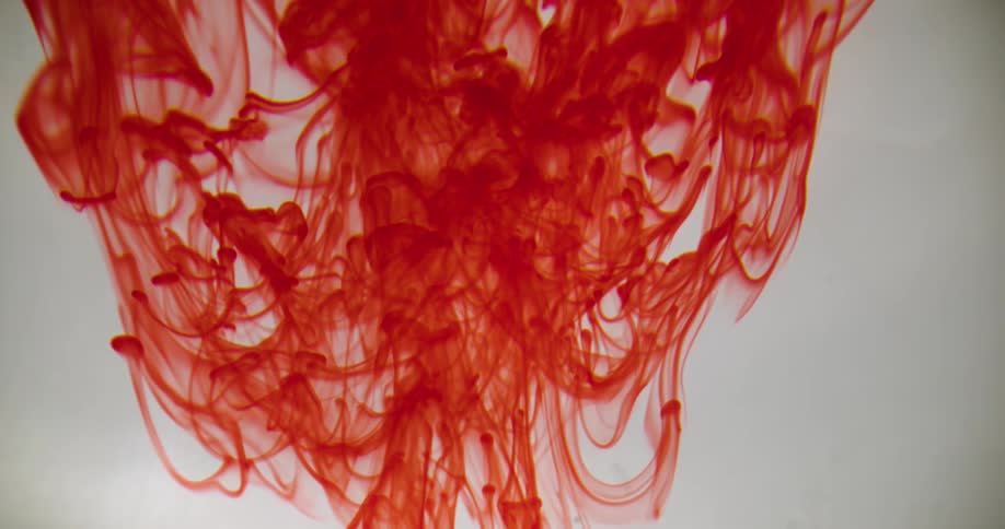 Bright red liquid ink blobs and strands floating up on water