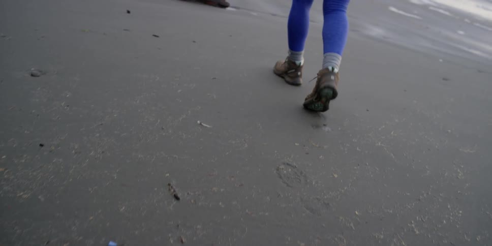 A person in blue leggings walks on the beach