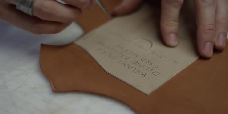 A man is carving into leather with a tool