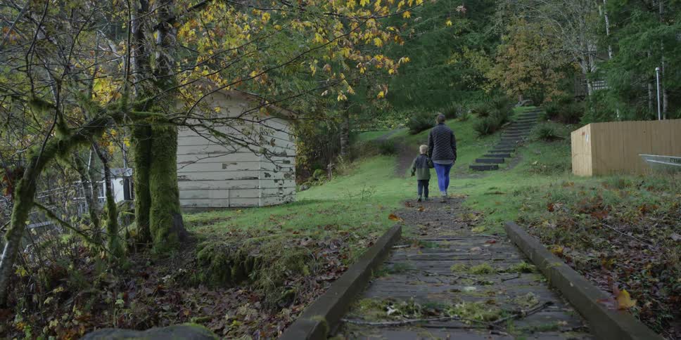 A woman and a boy walk up a path in the woods