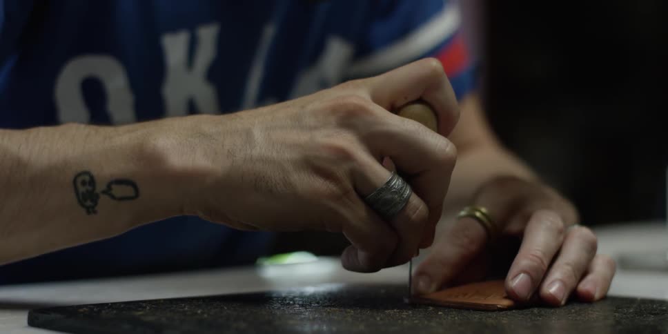 A man pokes a square of leather with a tool