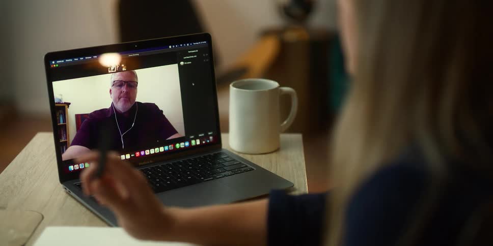 People talking on a video call through a laptop over a desk