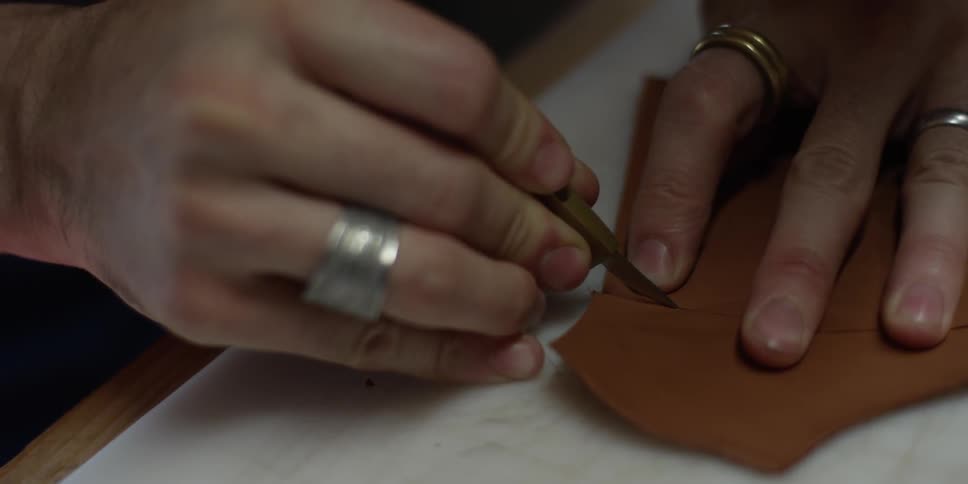 A man carefully cuts a piece of leather