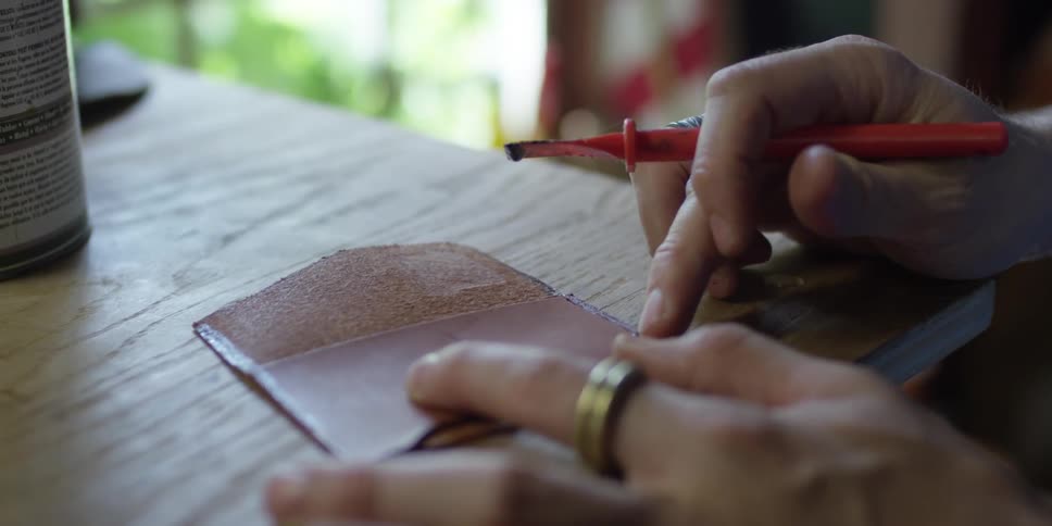 A person glues a square of leather