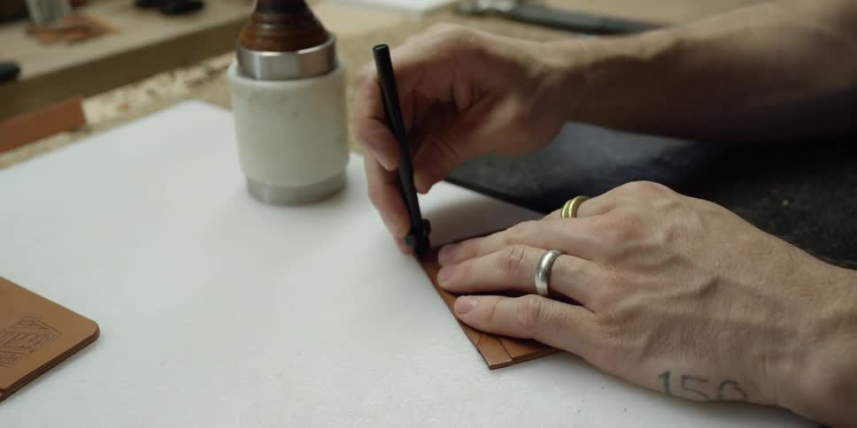 A person stamps a square of leather