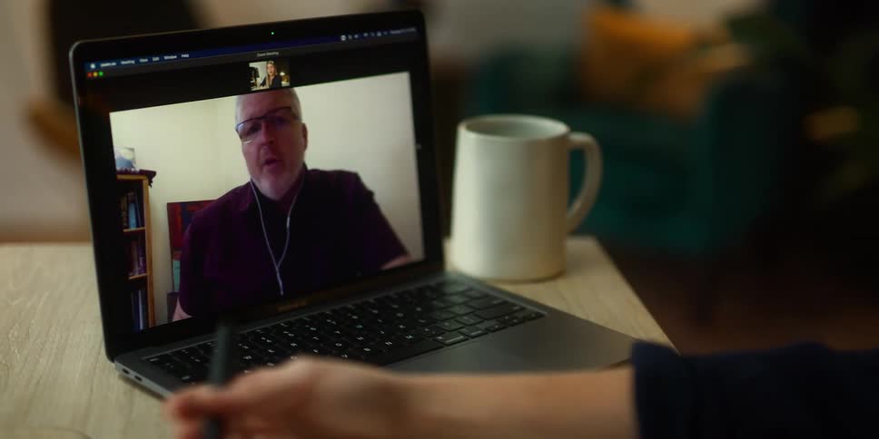 A woman is sitting in a cafe and video chatting with someone