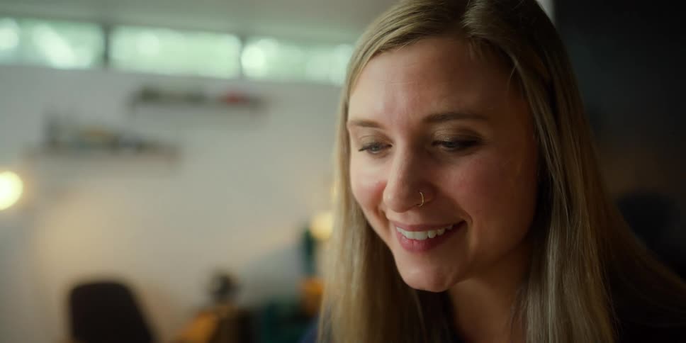 A woman smiles nods and waves as she talks during a video call