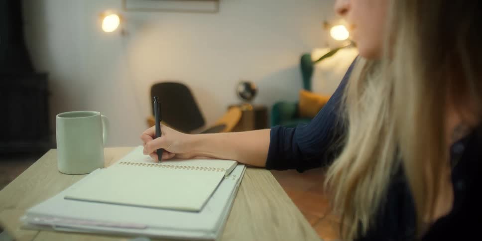 A woman taking notes in her room