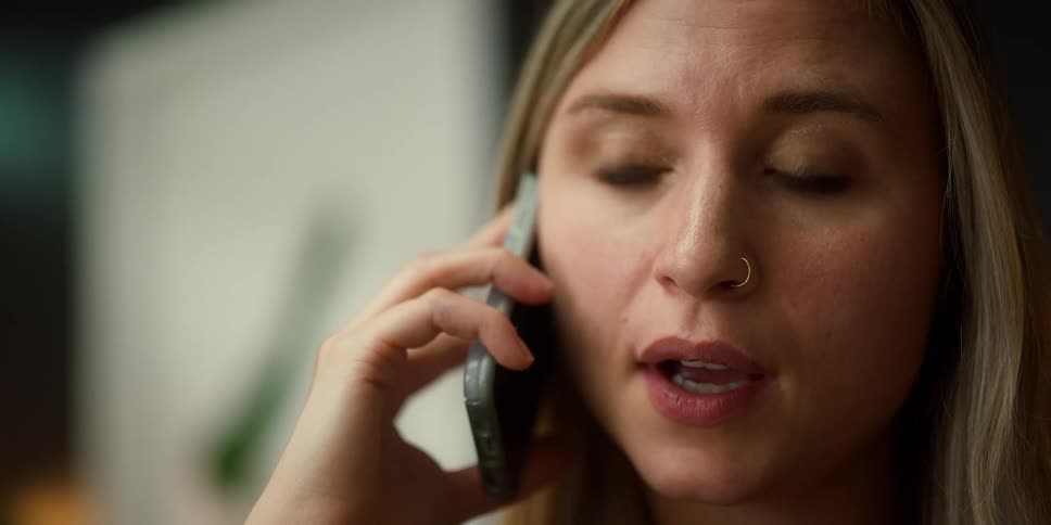 A woman is holding a cellphone to her ear and talking on it