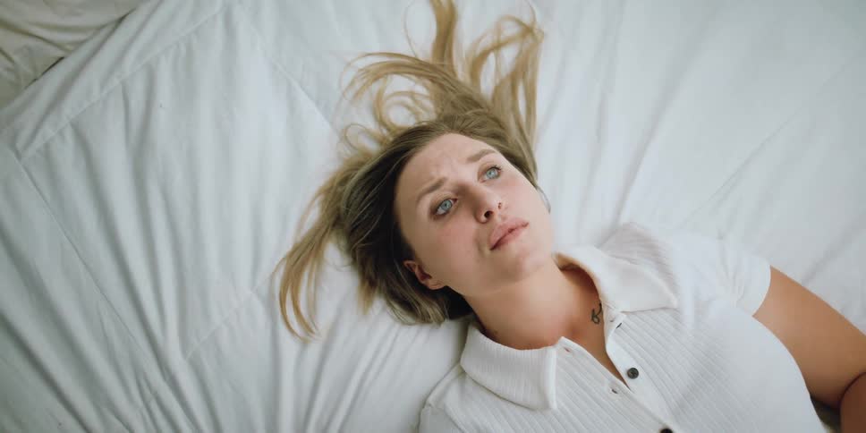 A woman laying on a white bed