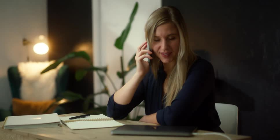 A woman answers her cell phone at the desk
