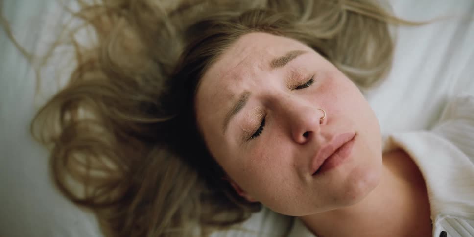 A woman closes her eyes tight and takes a deep breath as she cries