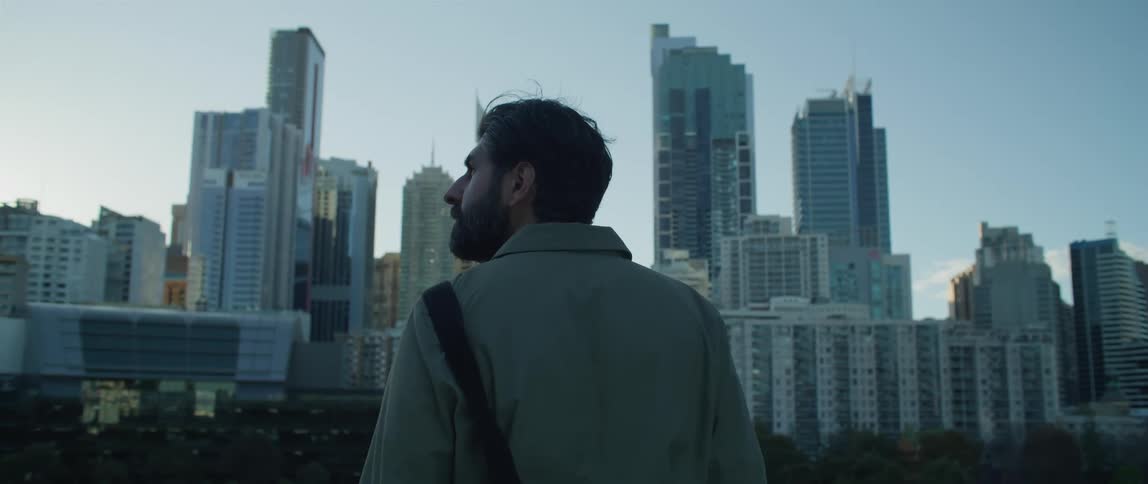 A man stands looking out at the city buildings and skyscrapers