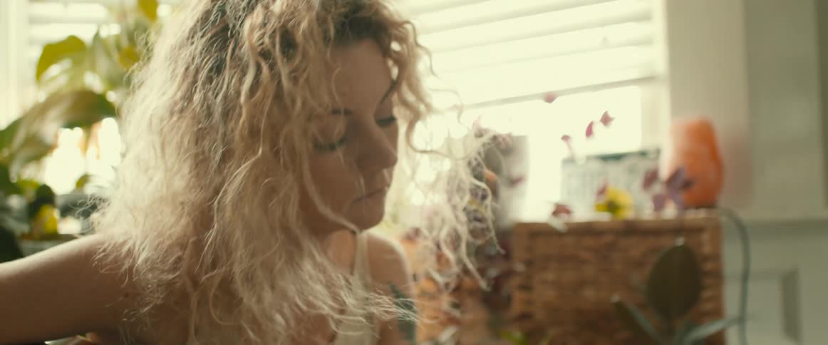 Blonde woman plays a guitar as the breeze gently blows her hair