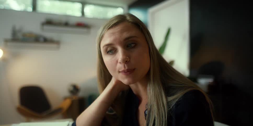 Blonde woman sitting in home office gestures while video conferencing