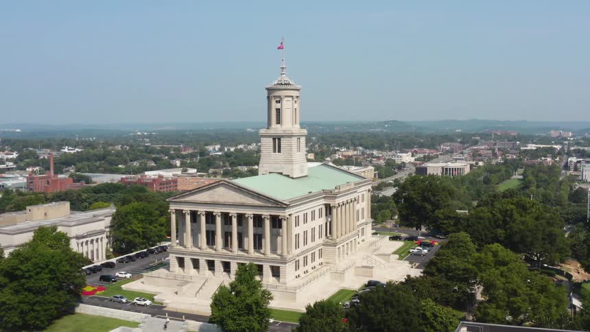 Flags fly high atop a columned building in a city