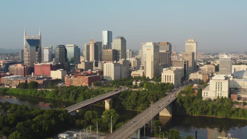 Traffic travels across a pair of bridges spanning a river in a metropolis during the day
