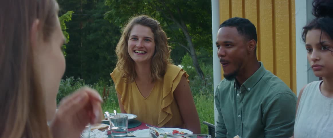A group of people are sharing a laugh as they enjoy a meal together outside
