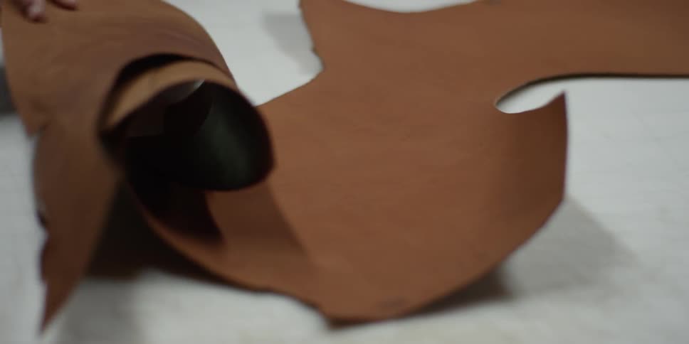 An artisan rolls out a large piece of leather