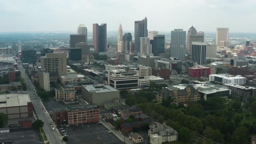 Cars parked in a parking lot with trees and city buildings nearby
