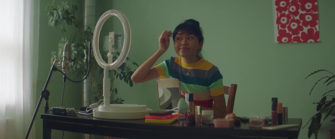 A woman is applying makeup as she films herself