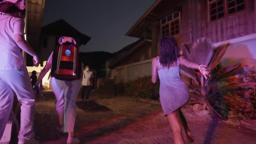 Group of friends running into the backyard of a home under flashing blue and red lights at night