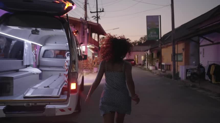 A woman running towards an ambulance with utility poles houses the sky and clouds in the background