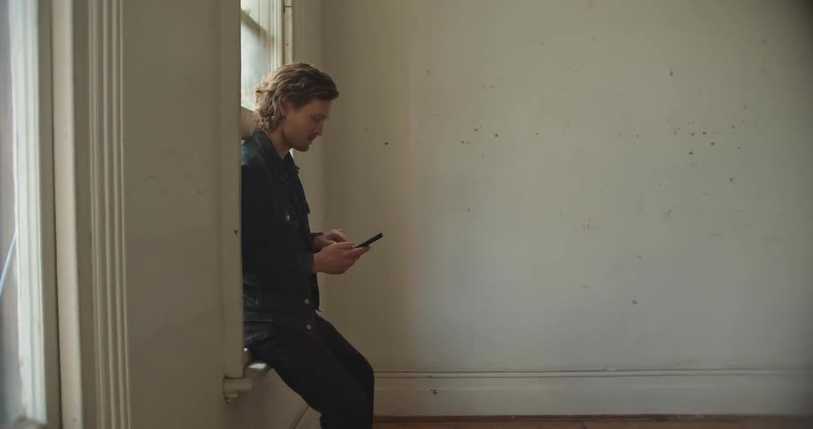 A man typing on a smartphone in a house