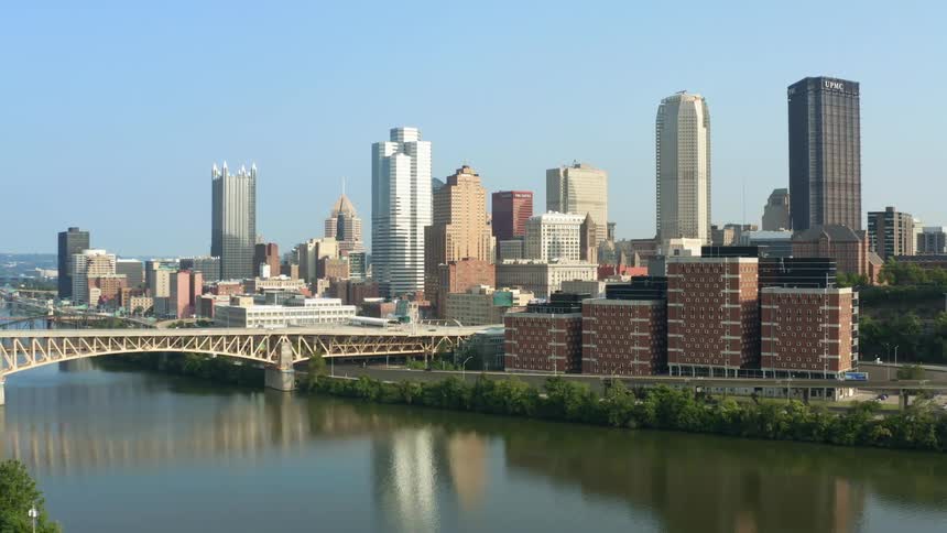 A city skyline full of buildings next to a river with a large bridge