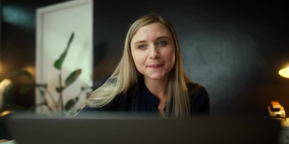 A woman waving at a computer