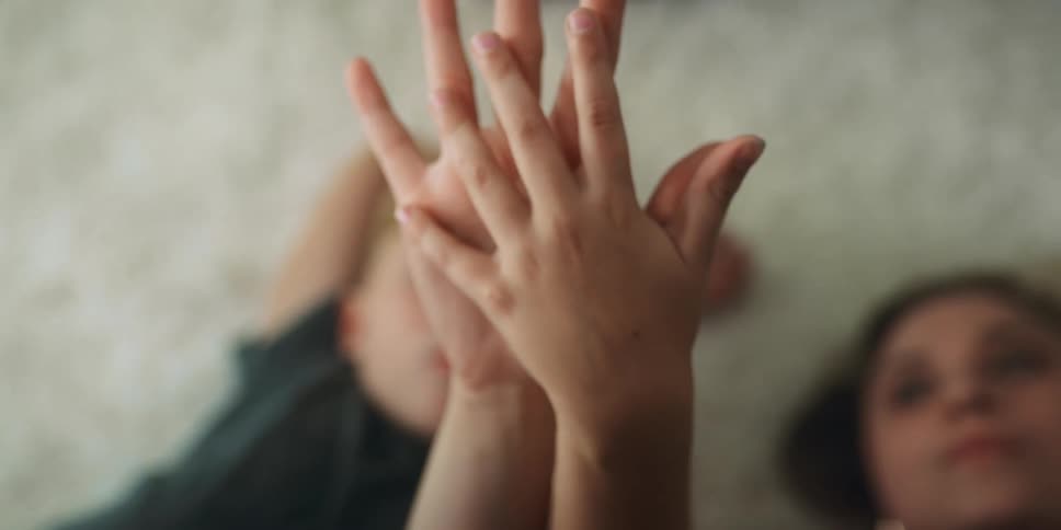 Mother and son holding hands while resting over a white rug on the floor of the living room