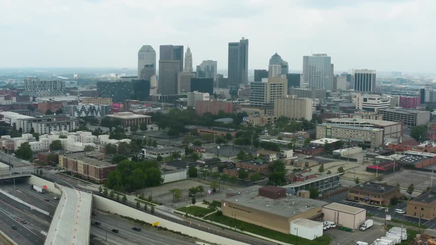 Aerial view of city skyline and vehicles driving on highways on a cloudy day