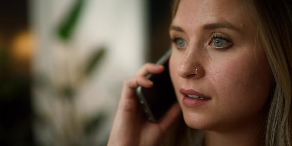 A woman is holding and talking on a cell phone indoors